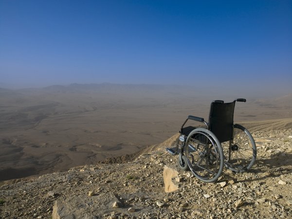 Empty wheelchair on cliff edge, desert