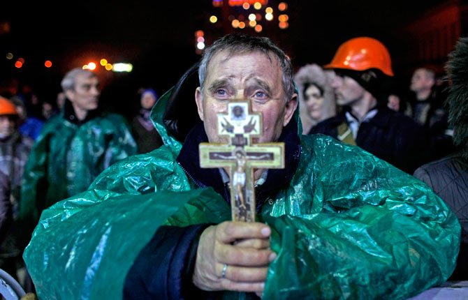 Ukraine Christian holds a crucifix as he prays in Kiev, Ukraine, Thursday, Feb. 20, 2014  The deposed President vowed to defeat "terrorists" responsible for seizing weapons and burning down buildings. AP Photo/ Marko Drobnjakovic