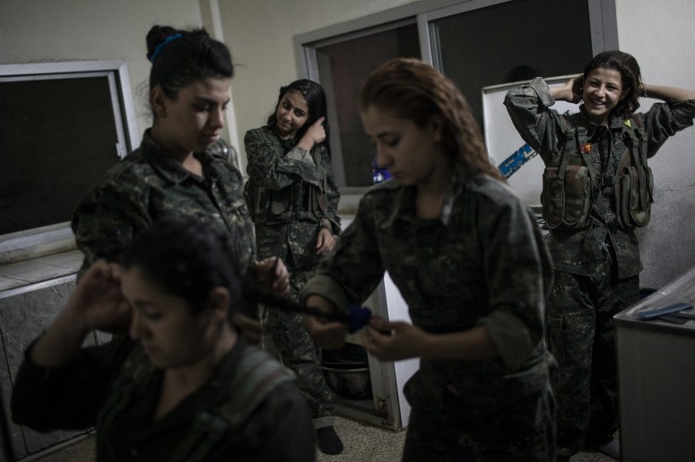 Young YPJ recruits Fix their hair at 4:30 AM before participating in training exercises and drills, near Derek City, Syria. 