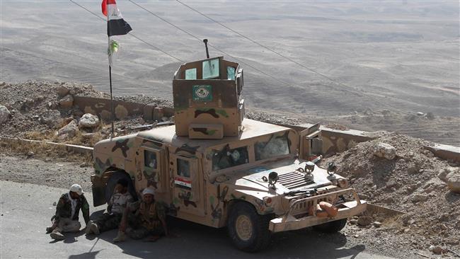 Iraqi fighters from the Popular Mobilization units, fighting alongside Iraqi forces, sit next to an armored vehicle during a military operation against Daesh militants in Makhoul Mountains, north of Baiji, on October 17, 2015. © AFP